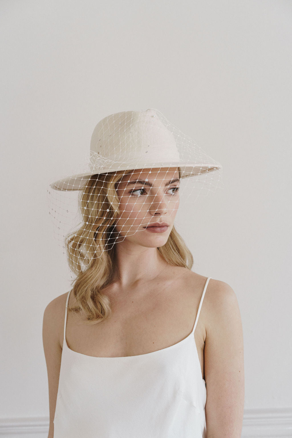 Beautiful model wears an ivory fedora hat with merriwidow veiling